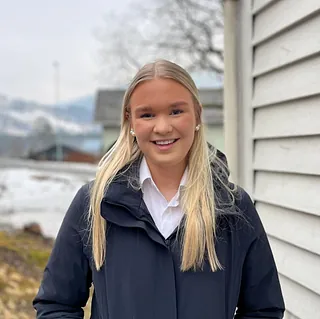 Bilde av blond kvinne ved hvitt hus