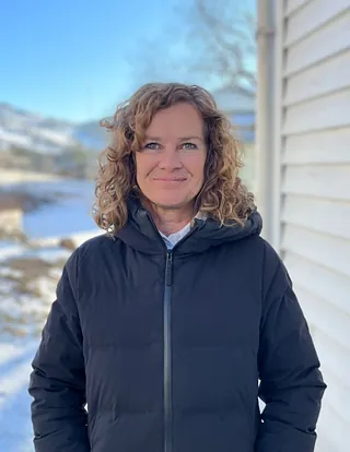 Kvinne med svart jakke og brunt krøllete hår